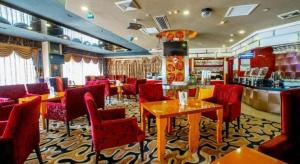 restauracja z czerwonymi krzesłami i stołami oraz barem w obiekcie Zhongshan Louis Hotel w mieście Zhongshan