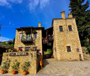 a large stone building with a balcony on top of it at Varnevo Guesthouse in Ano Trikala