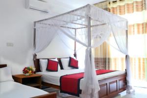 a bedroom with a canopy bed with red and white pillows at Unaway Holiday Home in Unawatuna