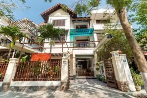 a house with palm trees in front of it at Kim's Villa Hoi An in Hoi An