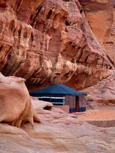 a tent in the desert next to a cliff at The Legacy of Wadi Rum in Wadi Rum