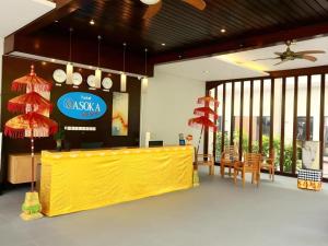 a restaurant with a yellow counter and chairs and windows at Asoka City Bali Hotel in Legian