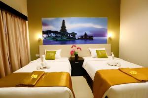 two beds in a room with a painting on the wall at Asoka City Bali Hotel in Legian
