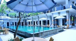a pool with an umbrella and tables and chairs at Asoka City Bali Hotel in Legian +149 photos