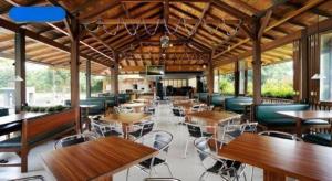 un restaurante con mesas y sillas de madera y muchas mesas en Jimmers Mountain Resort, en Puncak