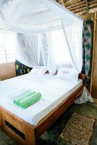 a bed with a canopy with a green towel on it at Kanga Beach Paradise in Mafia Island