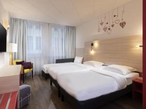 a hotel room with two beds and a chair at greet Berlin Alexanderplatz in Berlin