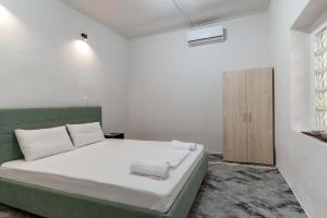 1 dormitorio blanco con 1 cama y armario de madera en Azure Nest, en Nea Peramos