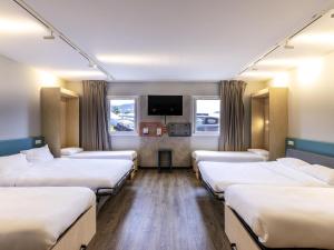 a hospital room with four beds and a flat screen tv at ibis Budget Millau Viaduc in Millau +143 photos