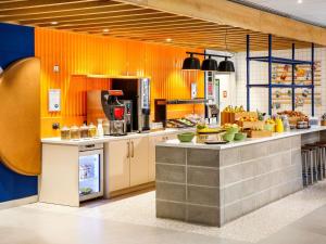a kitchen with orange walls and a counter with food at ibis budget Manchester Airport T2 in Hale