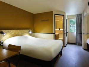 a hotel room with a large bed and a table at Greet Hôtel Villeneuve la Garenne - rénové in Villeneuve-la-Garenne