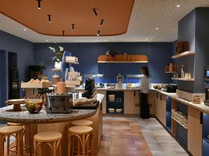 a woman standing in a kitchen with a counter at Ibis Styles Charleroi Airport Aero 44 in Charleroi