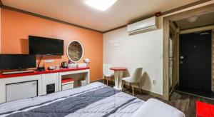 a bedroom with a bed and a desk and a tv at Dubai Motel in Daejeon