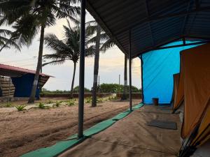Un edificio azul en la playa con palmeras. en Zone 51 Malpe - Beach Camping, en Udupi