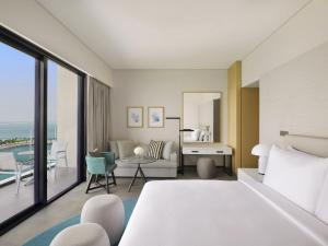 a bedroom with a bed and a living room at Mövenpick Resort Al Marjan Island in Ras al Khaimah