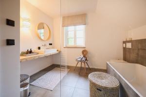 a bathroom with a sink and a tub and a mirror at Ferienwohnungen Haus Rose Marie - Your Austrian Home in Grundlsee +19 photos