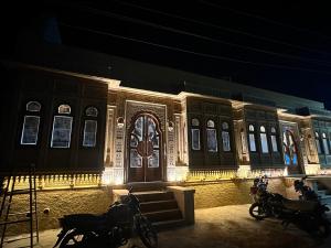 ジャイサルメールにあるHotel Golden Safariの夜にライトアップされた建物の前にバイクが駐車されている