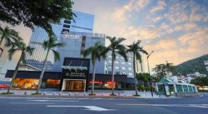 a building with palm trees in front of a street at Downtown Hotel in Zhuhai