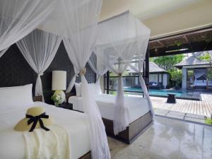2 camas con cortinas blancas en un dormitorio en Peppers Seminyak, en Seminyak 52 fotos más