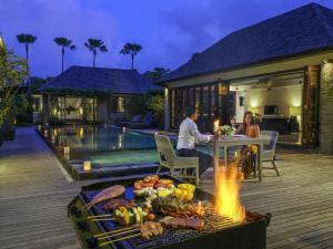 un hombre y una mujer sentados en una mesa frente a una casa en Peppers Seminyak, en Seminyak