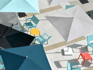 eine Draufsicht auf Stühle und Tische mit Sonnenschirmen in der Unterkunft ibis Budget La Rochelle Centre gare in La Rochelle