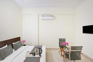 Una habitación de hotel con una cama, una mesa y sillas. en Hotel O Star Key Sliver crest hospital, en Gurgaon