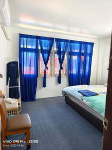 a bedroom with blue curtains and a bed with a chair at Banphe​ Hostel in Ban Phe +37 photos
