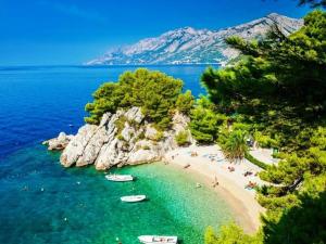 a beach with people and boats in the water at Nature Beauty with pool and whirlpool in Zagvozd