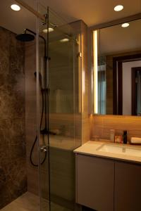 a bathroom with a glass shower and a sink at Lancaster Legacy Hotel & Apartments in Ho Chi Minh City