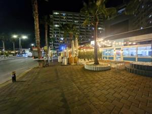 un trottoir avec des palmiers et un bâtiment la nuit dans l'établissement דירת נופש חלומית, à Ashdod