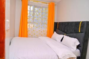 a bedroom with an orange window and a bed at gilgalhomes in Gatunga