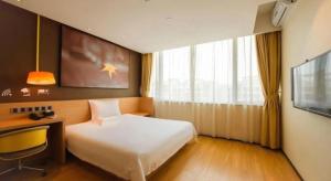 a bedroom with a bed and a desk and a tv at IU Hotel Tianjin Fumin Qiao Branch in Tianjin