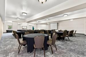 a conference room with tables and chairs and a screen at Clarion Suites Anchorage Downtown in Anchorage