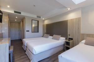 a hotel room with two beds and a table at Hotel Civera in Teruel +37 photos