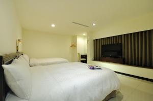 a hotel room with a white bed and a flat screen tv at 安可旅店 Bravo Hotel in Taichung