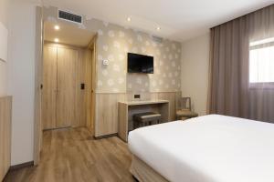 a bedroom with a bed and a desk and a tv at Hotel Civera in Teruel