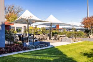 a patio with tables and chairs and umbrellas at Hotel Elms Christchurch, an Ascend Collection Hotel in Christchurch
