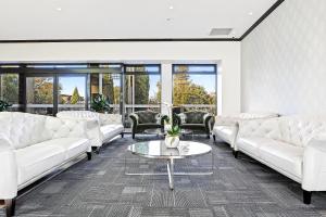 a living room with white couches and a table at Hotel Elms Christchurch, an Ascend Collection Hotel in Christchurch