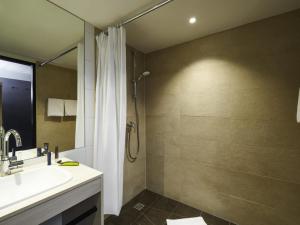 a bathroom with a sink and a shower with a shower curtain at Ibis Styles Singen in Singen +32 photos