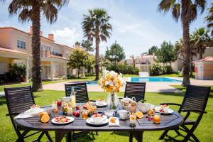 - une table avec de la nourriture dans une cour avec des palmiers dans l'établissement The Village – Praia D’El Rey Golf & Beach Resort, à Casal da Lagoa Seca