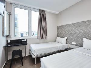 a hotel room with two beds and a window at ibis budget Singapore Ruby in Singapore +18 photos