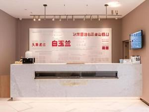 a lobby with a white counter with writing on the wall at Magnotel Business Harbin Railway Station Qiulin Museum Metro Station in Harbin
