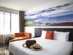 a hotel room with a bed with a hat on it at Novotel Devonport in Devonport