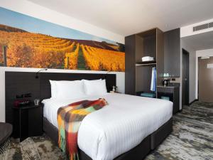 a bedroom with a large bed with a painting on the wall at Novotel Devonport in Devonport +101 photos