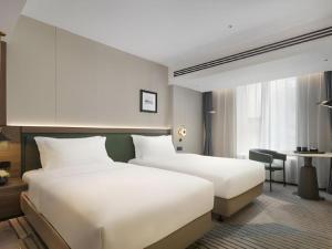 a hotel room with two beds and a desk at Aden Select Shenzhen Taizi in Shenzhen
