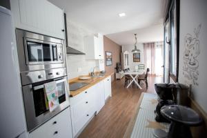 a large kitchen with white cabinets and a television at Atico Aligma in Granada