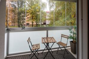 two chairs and a table on a balcony with windows at Luxury apartment with WiFi and Netflix Ostrava-Jih in Hrabŭvka