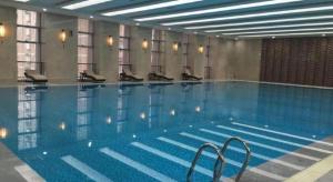 a large swimming pool with chairs in a building at New Century Grand Hotel Xi'an Xizang Building in Xi'an
