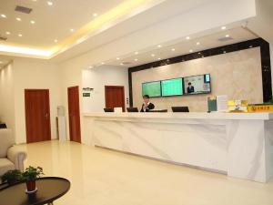 a woman sitting at a reception desk in a lobby at GreenTree Alliance Yichang East Yichang Station Hotel in Yichang