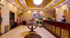 Un hombre de pie en un mostrador en un vestíbulo. en GreenTree Inn Hefei Huangshan Road Business Hotel, en Hefei